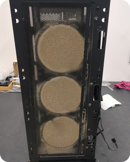 Painel frontal de gabinete de computador com três filtros de poeira redondos tomados por sujeira antes do processo de limpeza.